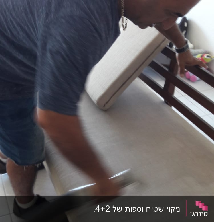 אדם מנקה ספה עם שואב אבק